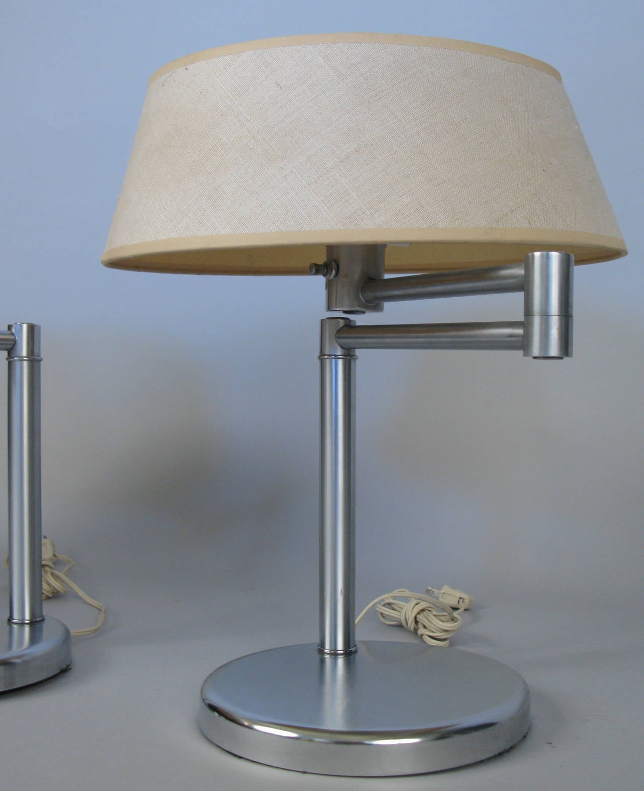 A matched pair of Classic vintage modern 1960s swing arm lamps in brushed steel with their original shades and diffusers. Each lamp has a double socket and they are both in very good condition. Stamped Nessen.