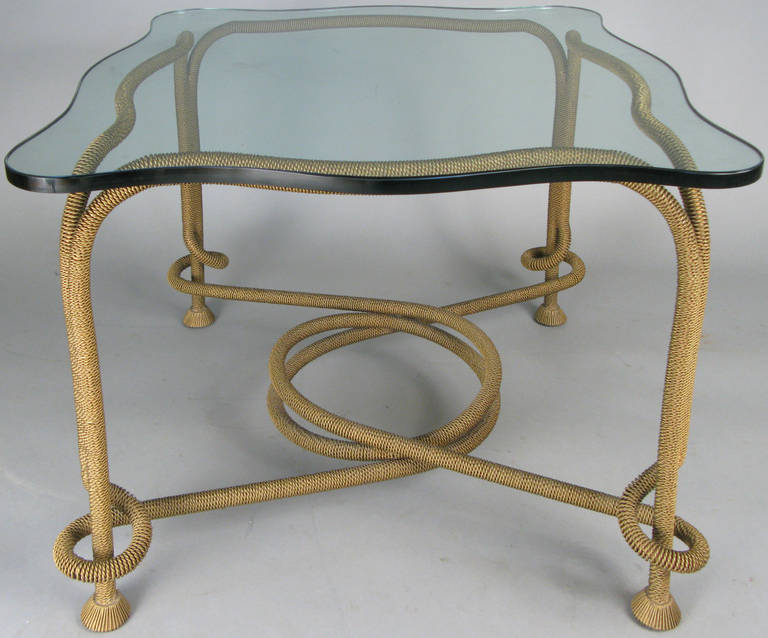 an amazing cocktail table with a base in the form of twisted brass coils of rope, supporting a thick glass top with scalloped edges. mint condition.