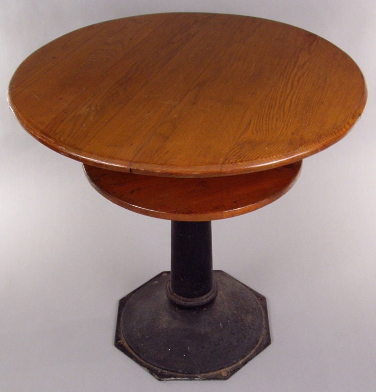 a handsome antique round 'speakeasy' or 'prohibition' table, these were used during prohibition in bars so that if the cops came around, patrons would move their drinks to the lower hidden shelf below the tabletop. beautful cast iron base and oak