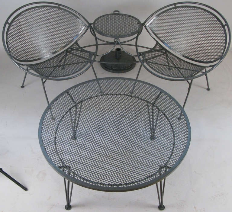 a vintage wrought iron tete a tete from Salterini's 'Radar' Collection. a pair of lounge chairs connected by a small table, together with a large round cocktail table from the same collection. the tete a tete also comes with the original very heavy