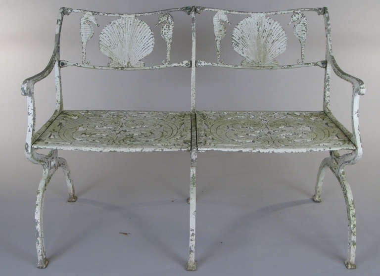 A vintage 1950's cast aluminum garden bench in a beautiful design with large seashell & seahorse motif with remnants of original paint.