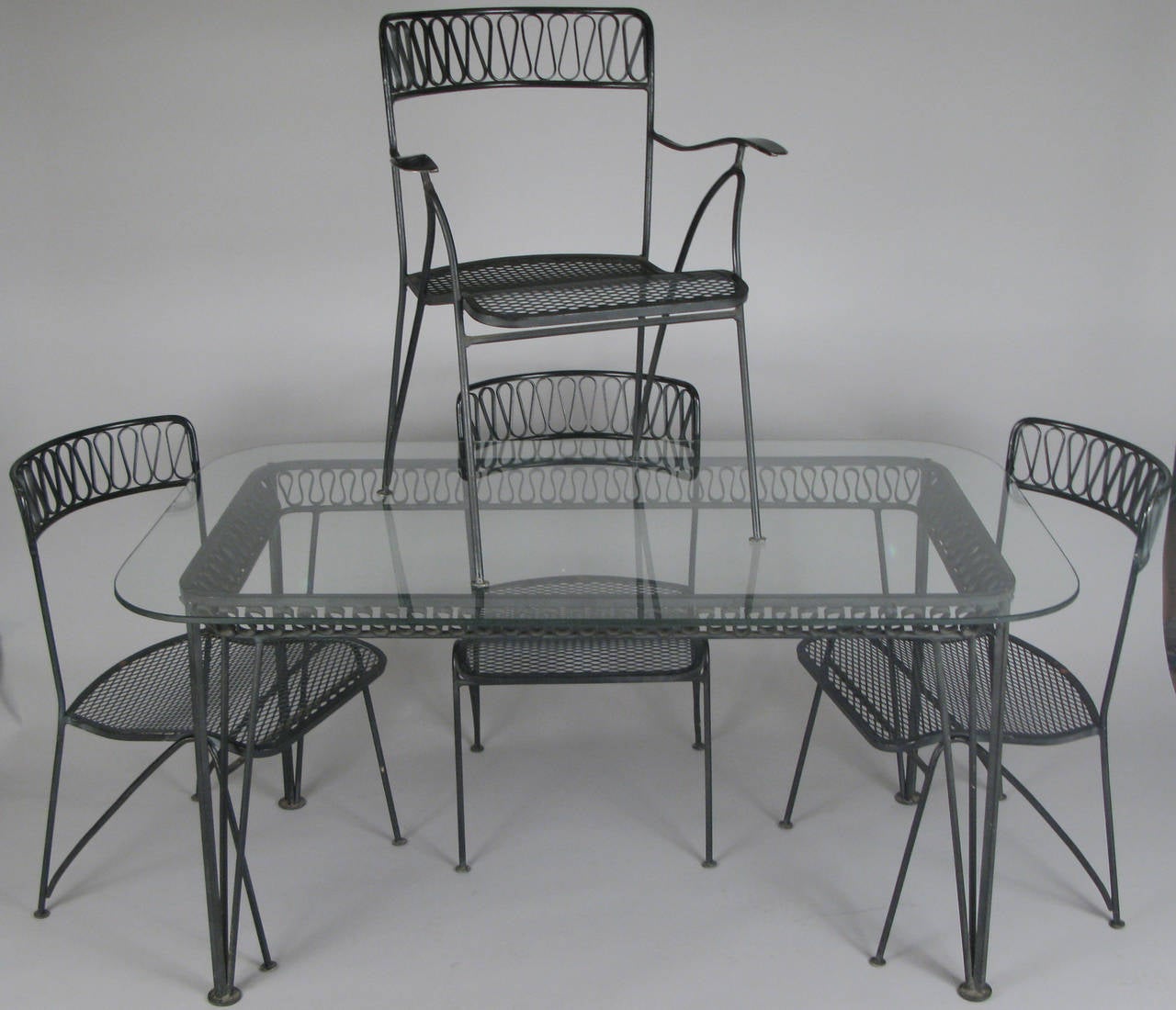 A Classic and iconic Salterini 'Ribbon' dining set from the 1950s, designed by Maurizio Tempestini. One of his best modern designs, with heavy and well made wrought iron frames and his dynamic wrought iron ribbon detail in the curved backs of the