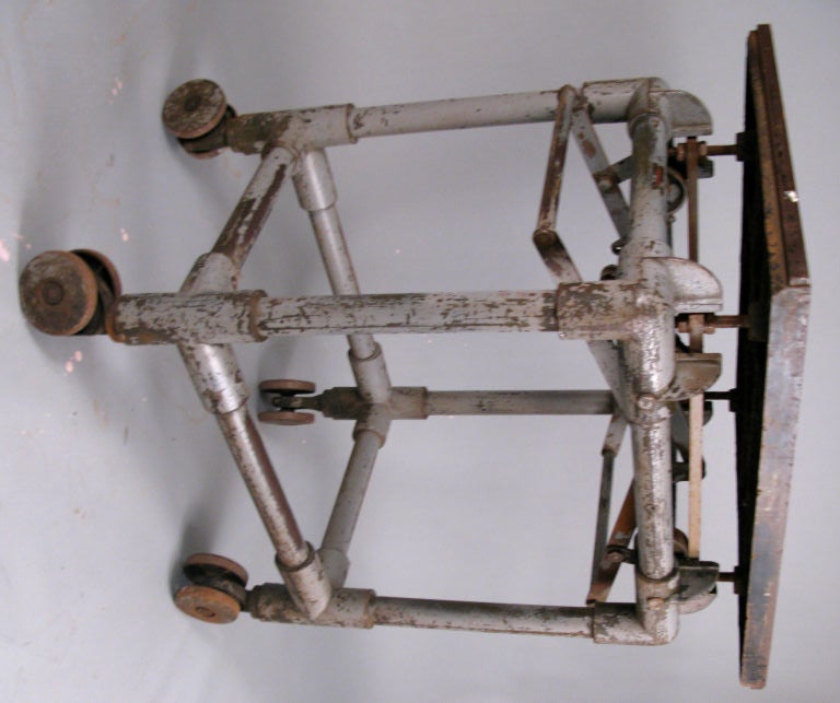 a very unusual antique rolling printer's table. cast iron wheels support an open frame and an adjustable mechanism that supprts the steel top. great form and very well made.