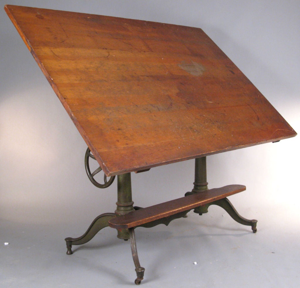 an outstanding antique early 20th century cast iron drafting table by Dietzgen. This is one of their most impressive tables, with an elaborate cast iron base with a curved and scrolled center section, and curved legs at either end. the top is