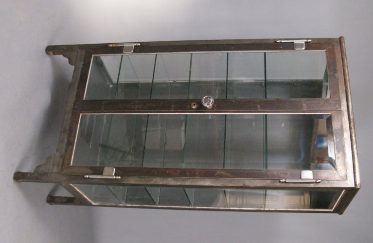 an outstanding antique steel & glass apothecary cabinet. beautiful simple tall form with glass doors and sides and six glass shelves. this is one of the best forms from the early 20th century, mounted on cast iron wheels with very nice steel hinges