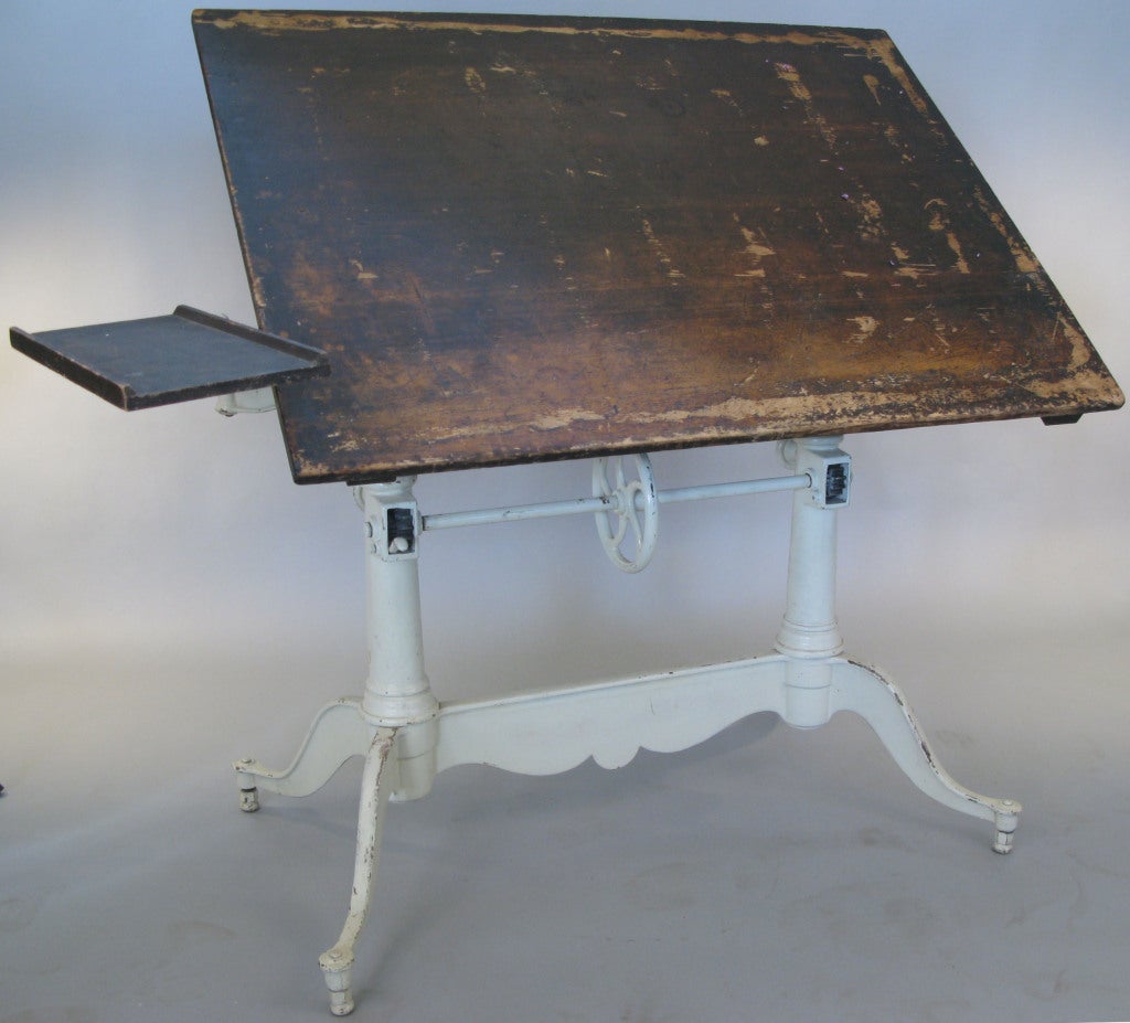 an exceptional antique cast iron double pedestal drafting table by Keuffel & Esser, with a beautiful detailed base having a center wheel for height adjustment, and a sliding locking mechanism for tilt adjustment. this handsome table also has the