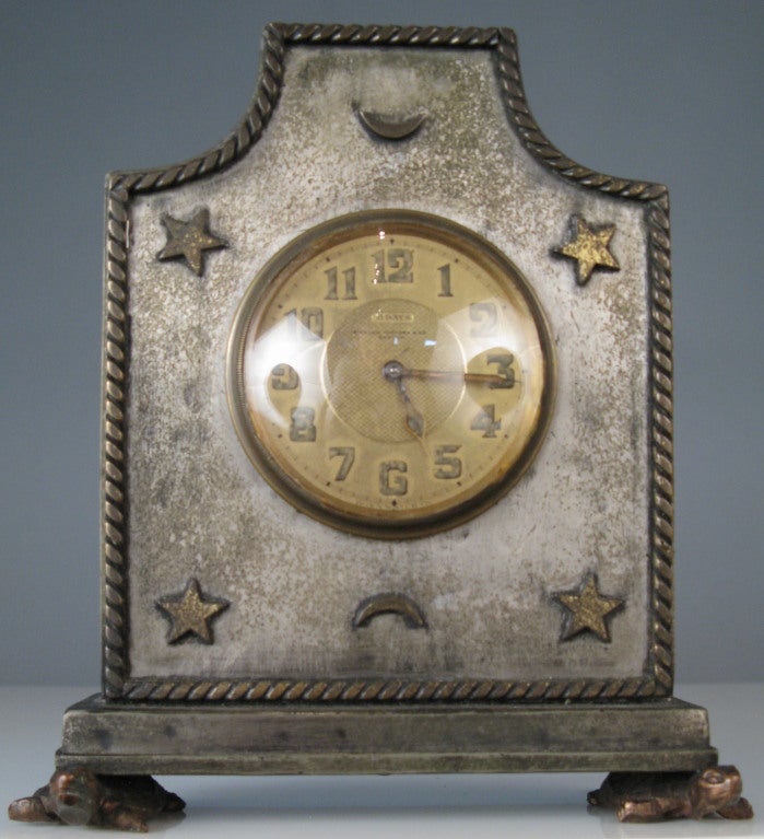 a charming antique 1930's mantle clock made by swiss clockmaker Doxa. very sweet case in brass decorated with stars and moons, and the case raised on bronze turtle feet.