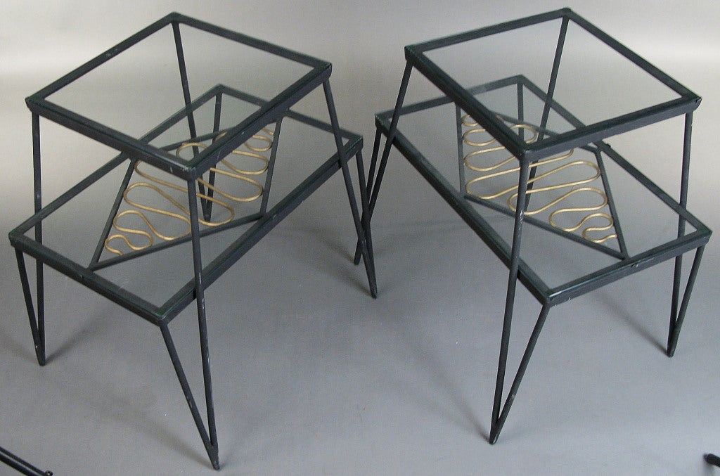 a very unique pair of vintage 1960's tables with bases in wrought iron, 2 glass shelves, and a lovely gilt gold ribbon design inset under the lower shelf. great touch of glamour on these very well made tables.