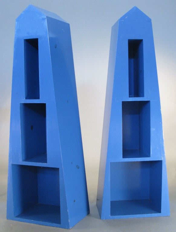 a matched pair of pyramid shaped bookcases in blue lacquer custom made for art patron and Warhol protege Fred Hughes. Reminiscent of Memphis design, the form, design, and color all play a part in these engaging functional objects.