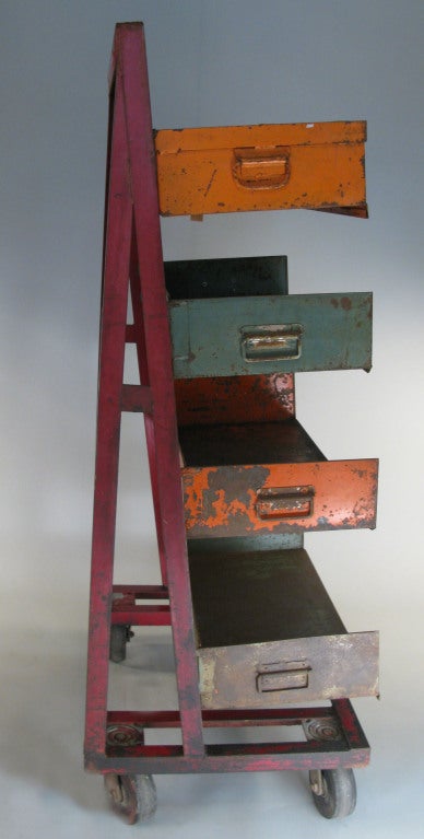 an antique industrial steel adjustable rolling storage rack, with a steel frame with angled mounting bar, and four 3 sided storage boxes that hang securely on the rack. these boxes can be placed at varying heights depending upon the items they are