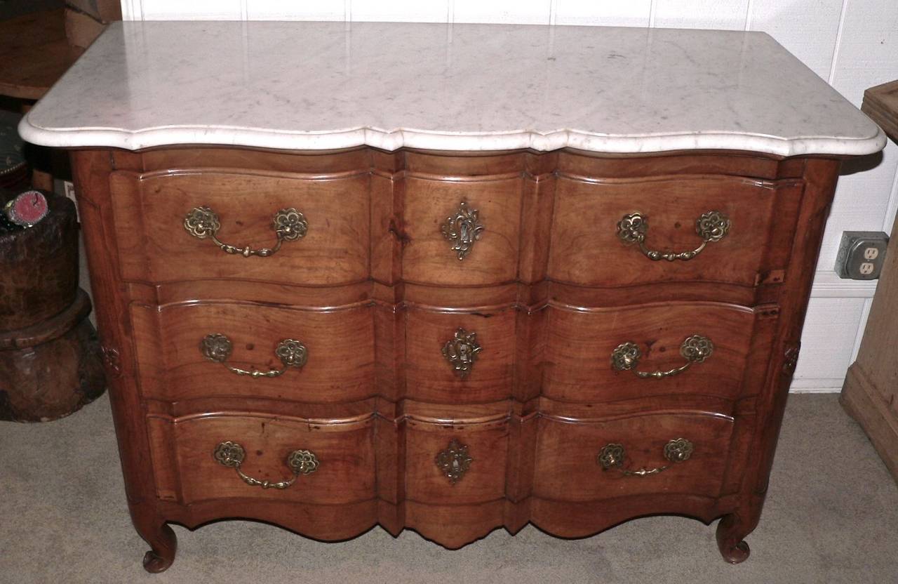 This commode Galbee has a beautiful color and patina and is made from the light colored, clear walnut typical of the Rhone Valley. The scalloped marble top is clear of markings and is original to the base. It has shaped side panels along with