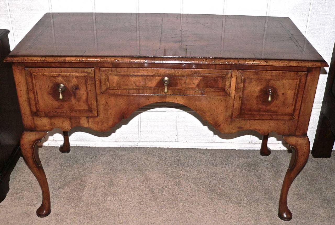 This very pretty ladies dressing table is veneered in walnut which is quartered on the top with crossbanding and featherbanding on both the top and drawers. It has cabriole legs with a pad foot. The drawers are oak lined and dovetailed which denotes