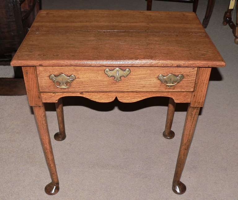 This unusally small mid 18th Century country table has a very pretty faded oak color with an scalloped apron and original brass handles.  It's in excellent condition with no blemishes to report.