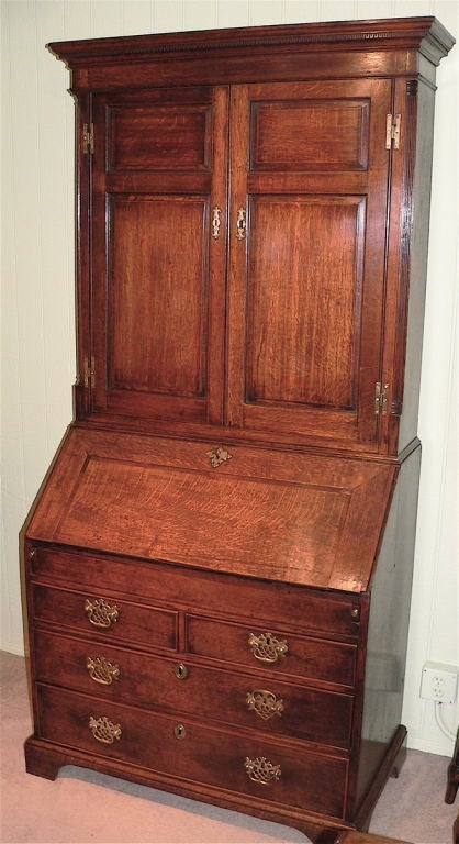 This Bureau Bookcase is of a provincial origin and features walnut crossbanding on the fall along with fielded panels on the top cabinet. The corners of the top have reeded quarter pillars which is a give-away to its date. The interior has a well