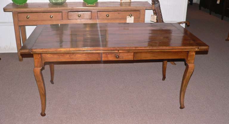 Made in the mid 19th Century, this rare type of farm table extends to 135'' with both leaves extended. It has a very attractive pale faded cherry color and is in great condition with the leaves being solid and smooth running. The apron has been