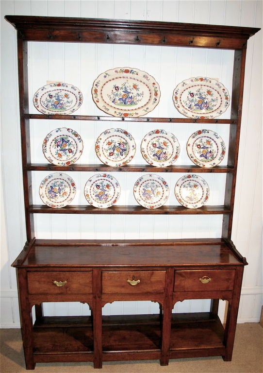 A unusually small scale  Welsh Dresser from South Wales  with three drawers and a bottom shelf of pine used to store crockery.  Original cup hooks on all but the bottom shelf. The plate rack is original to the base which is unusual for the top racks