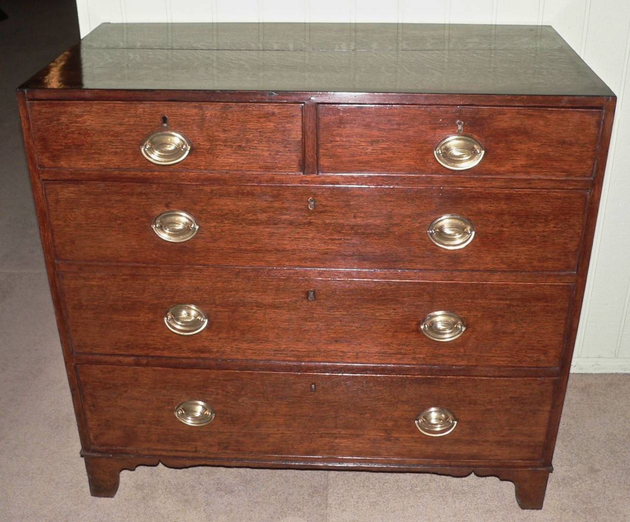 Made from quarter saw oak with the top crossbanded in mahogany, this chest is a very clean and tidy example dating from circa 1835. It has its original brass Hepplewhite oval handles along with unrestored original bracket feet.
The top is mark free