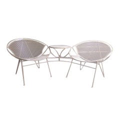An outdoor two seater with attached table by Salterini