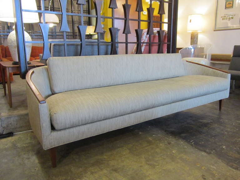 Beautiful large Danish Modern sofa with curved arms. The arms are trimmed in teak wood along with the legs.