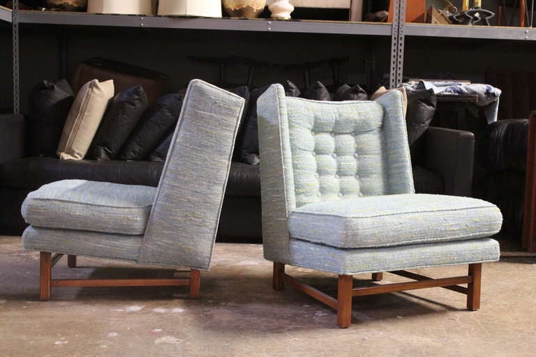 A pair of low lounge chairs with walnut bases. Very similar to a design by Edward Wormley for Dunbar.