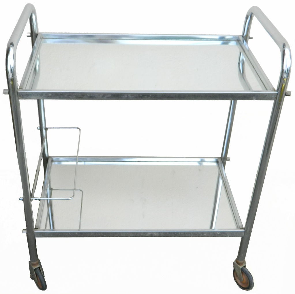 French two-tier bar cart in the manner of Jacques Adnet. Original mirror glass shelves and wheels.