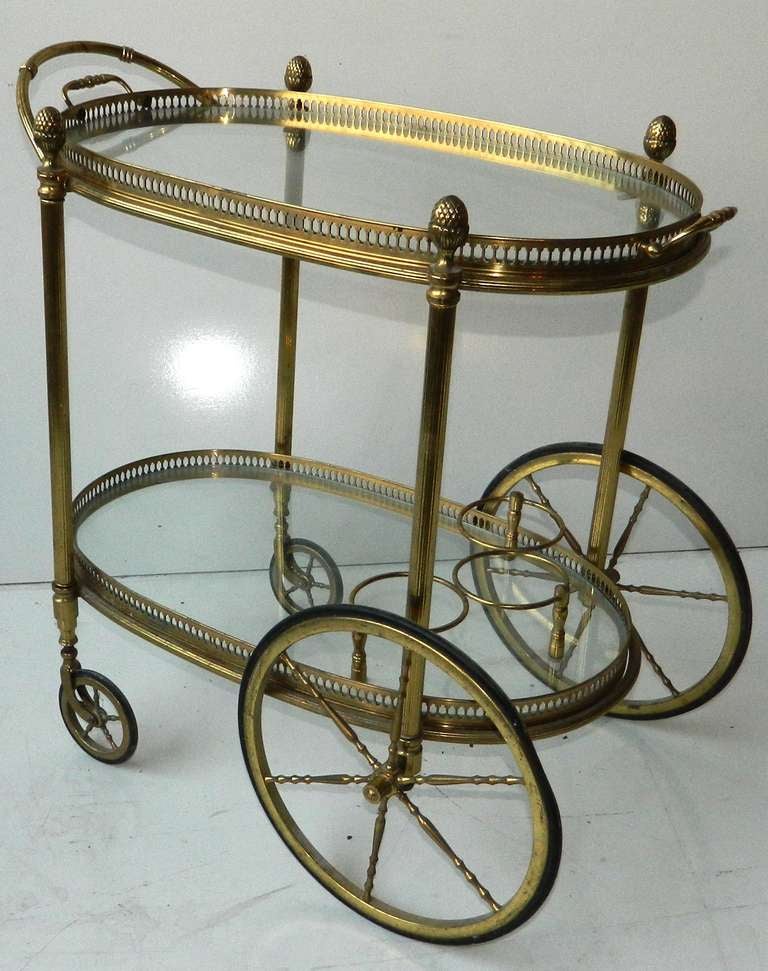 Very elegant C.1950'  heavy brass vintage bar cart.The 2 tray are removable. Nice detailing inluding bottle / decanter holders and top tray with handles. Finely cast galleries acorn finials give this piece a neoclassical flair.