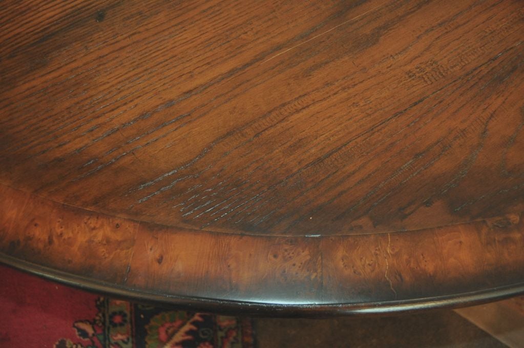 This large round table seats eight.  The banded table gives the table top a polished look as it sits on four columnar legs that lead to a platform.  The quadripple supporting feet end simple.  This table has plenty of leg room and makes a congenial