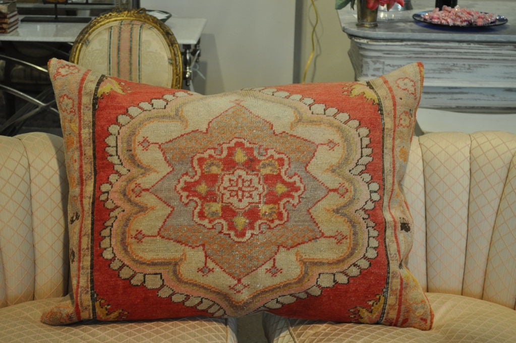This wool pillow with reds, oranges, and tans with a tan back has a zipper and makes the most of any furniture it sits on.