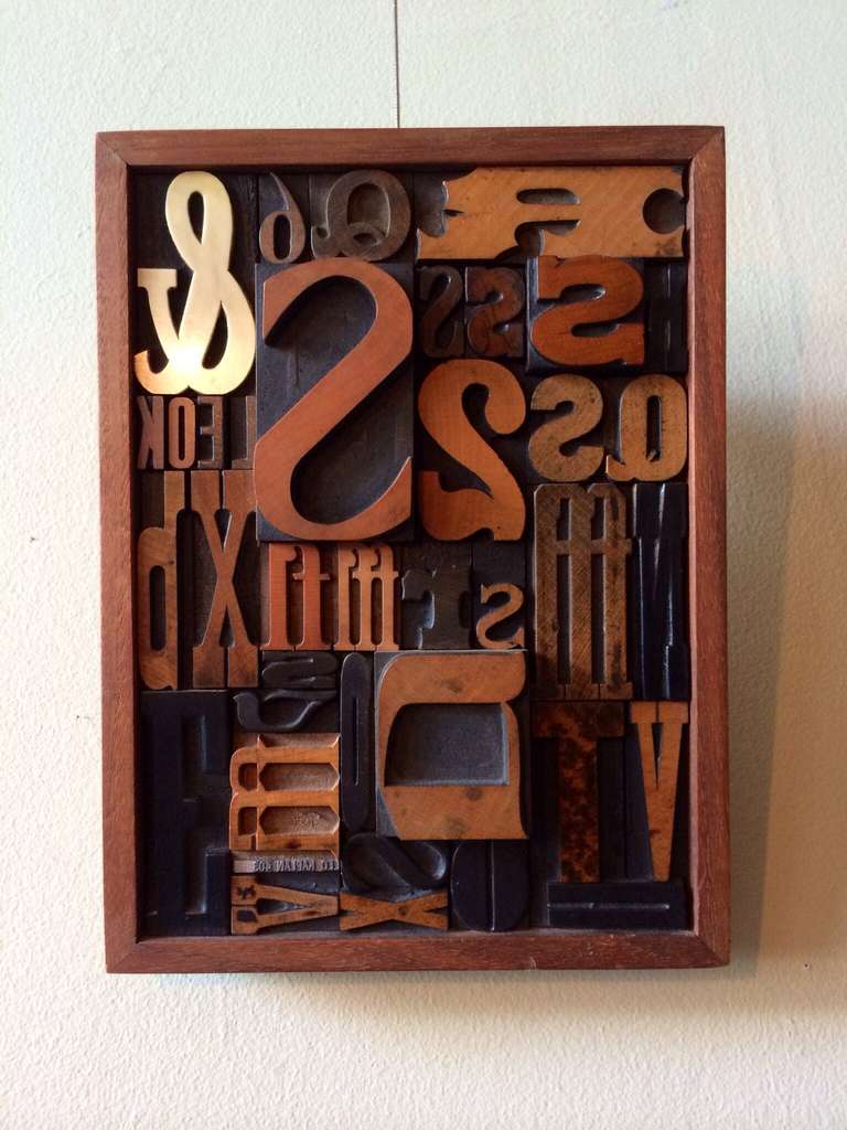 A walnut framed collection of antique wood and steel letterpress typeface blocks