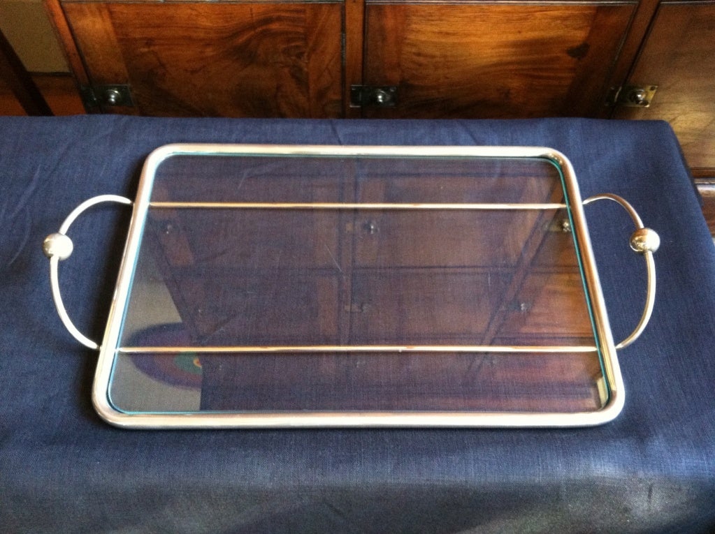A nickel tubular frame ball handled tray with inset glass surface