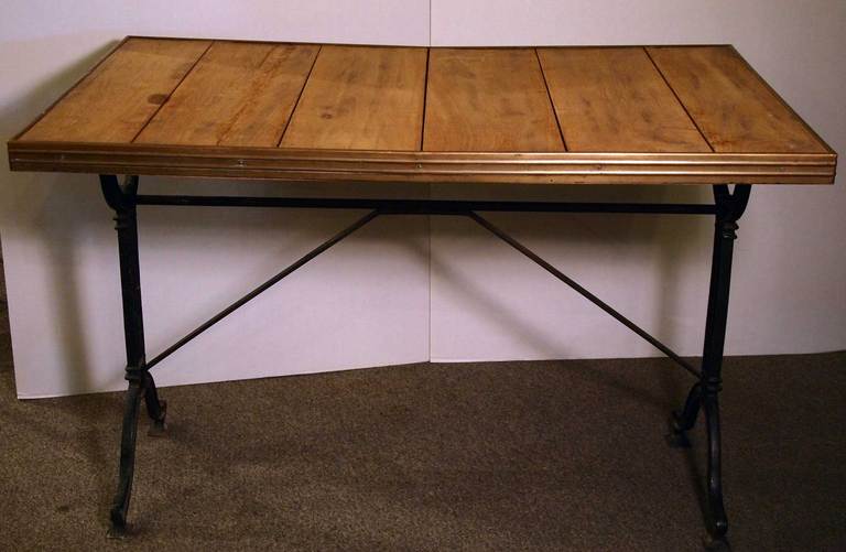 French bistro table with a brass rimmed oak wood top on a painted cast iron base