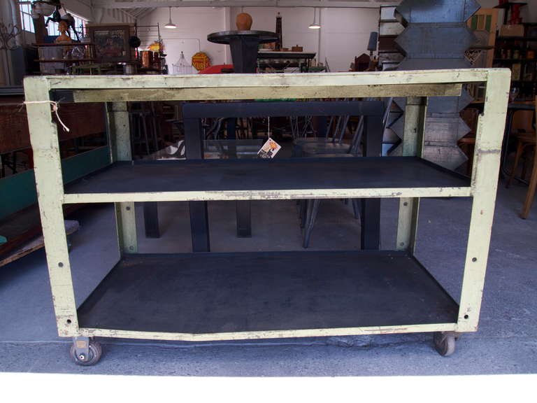 Machine shop green painted metal table with two shelves on castors.