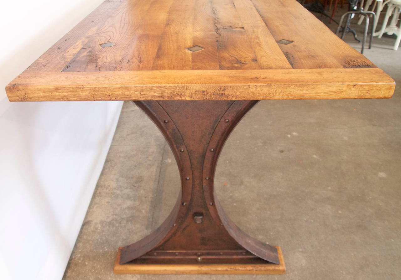 Wonderful counter/work height French industrial table with a thick oak top on shaped iron and tube iron base - 3 diamond iron supports that flush through top at each end, raised on oak plinths.  Late 19th/early 20th century