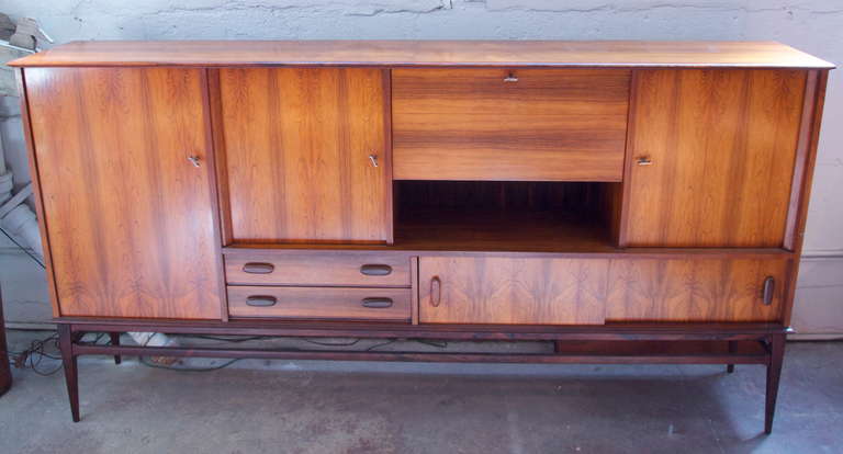 Elegant large & narrow geometric mid century Danish rosewood credenza with five compartments and two drawers raised on a slender base with tapering legs
Marked ARNO with Arnaud hardware