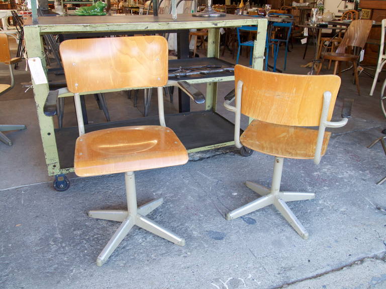 French industrial adjustable height armchairs.  Formed plywood, painted metal and black plastic armrests. 
 Circa 1970