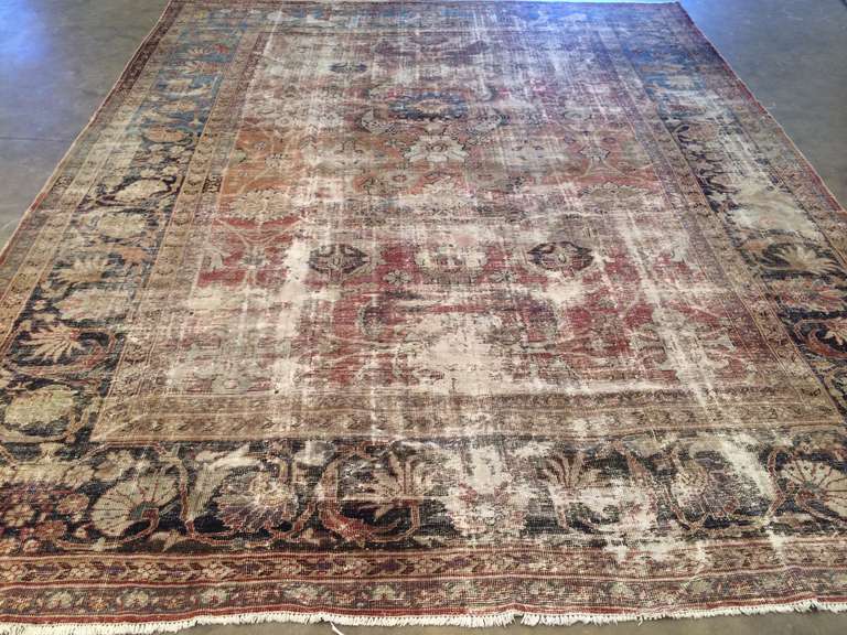 A colorful, inviting Mahal Distressed Antique Persian Rug. A border of curving vinery, stemmed flowers, and open blossoms encloses a field of repeating floral emblems and attaching vinery.