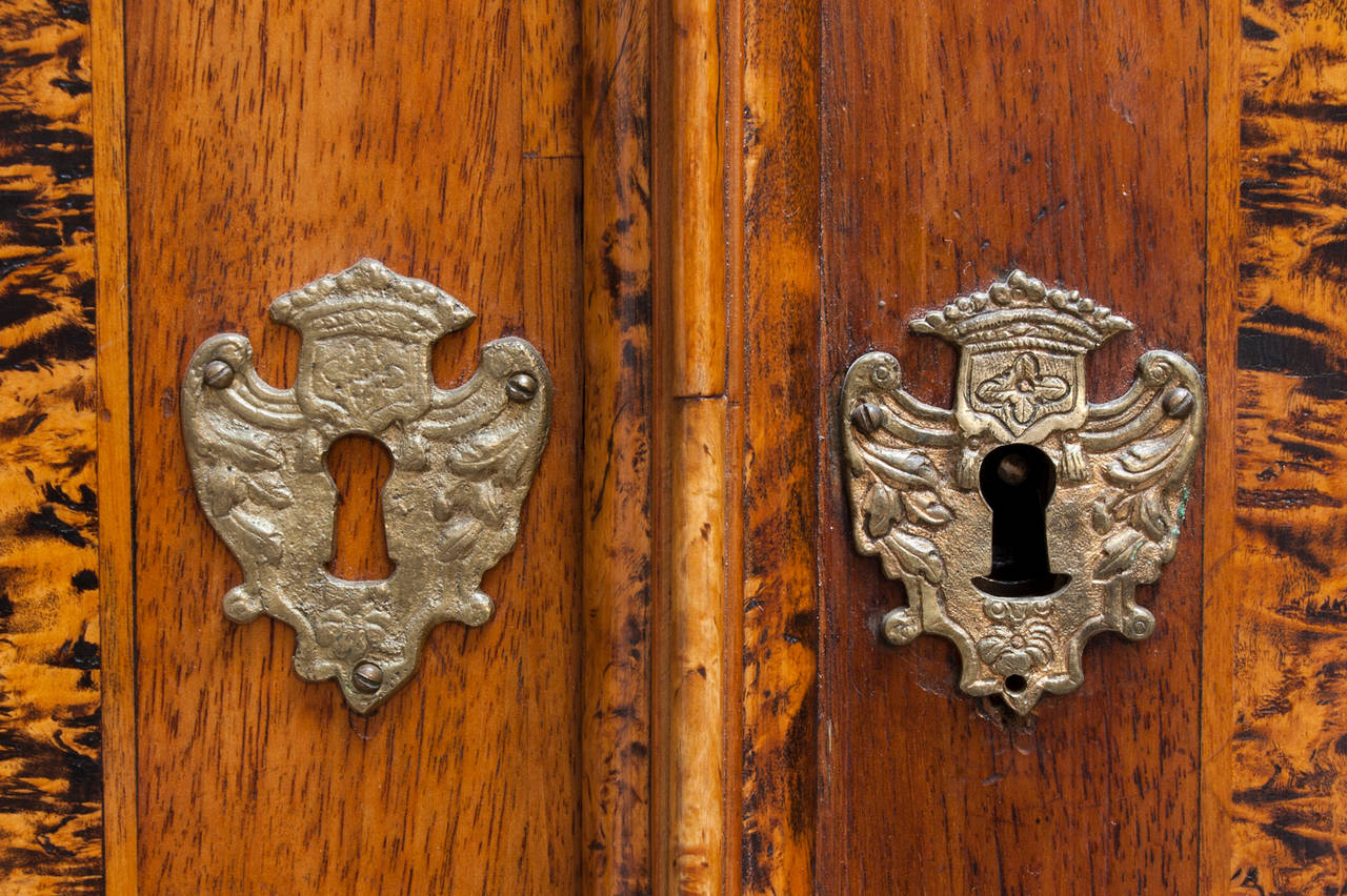 Baroque alder root cabinet with the crown's escutcheons and carved angels protruding in flight with the crown.