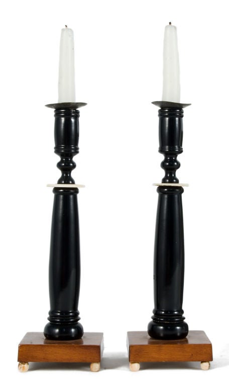 Pair of ebonised candleholders on a mahogany base with feet and a decorative detail made out of ivory.