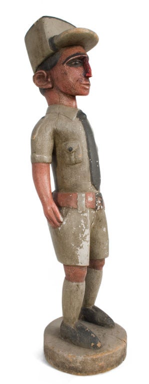 Carved wooden figure of a man in a kaki outfit.