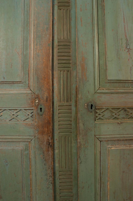 Two door Gustavian Armoir with intricate carvings in a worn pale green patina.