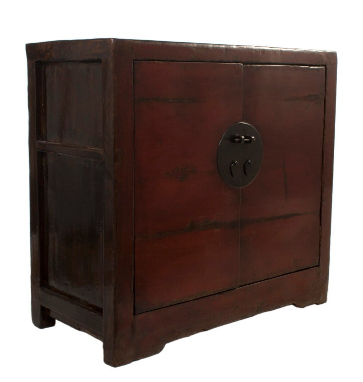 Lacquered Chinese Cabinet with two doors in a worn dark red patina.