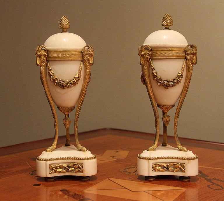 Very fine pair of Louis XVI style Napoleon III ormolu bronze and white alabaster cassolettes of ovoid form.  A pine cone finial crowns the top.
The pine cone finial lifts the alabaster round top to reveal an enclosed inverted candlestick