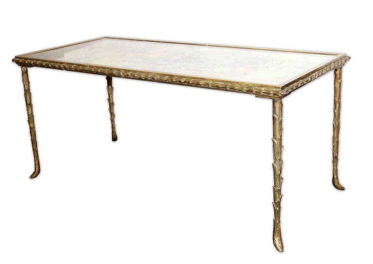 Maison Bagues - This very elegant Bagues coffee table is in its original condition - it has a gilt bronze, palm trunk motif frame and a églomisé mirrored top. The feet on each leg and the edge have a ram horn shape. The bronze has a beautiful