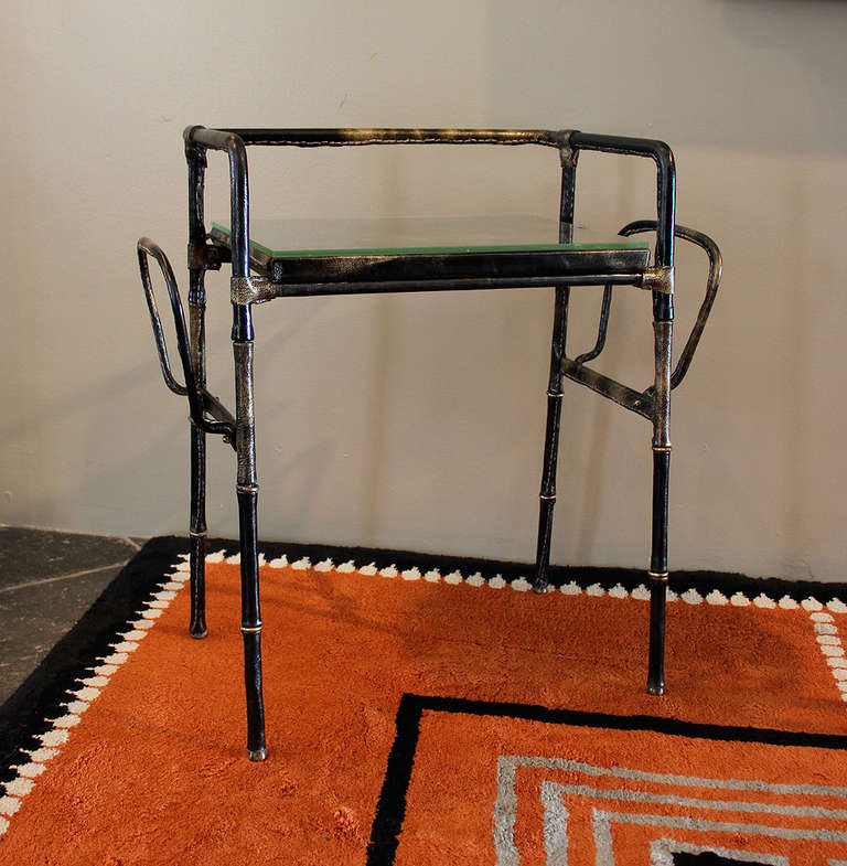 Jacques ADNET (1900-1984)

Rare occasional table in tubular metal covered in black saddle-stitched leather with a glass top that fits into two original aluminum brackets.
A magazine rack is located on each side.
Brass rings divide the leather