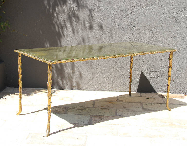 Maison Bagues, this very elegant Bagues coffee table is in its original condition. It has a gilt bronze, palm trunk motif frame and a églomisé mirrored top. The feet on each leg and the edge have a ram horn shape. The bronze has a beautiful