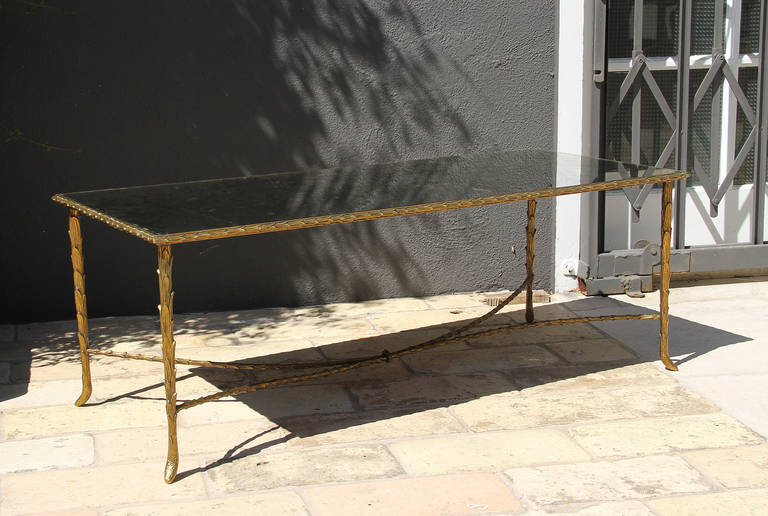 Maison Bagues, this very elegant Bagues coffee table is in its original condition. It has a gilt bronze, palm trunk motif frame and a églomisé mirrored top. The feet on each leg and the edge have a ram horn shape. The bronze has a beautiful