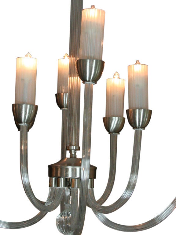 An elegant, ribbed glass and metal chandelier with fluted candle form and glass shades.