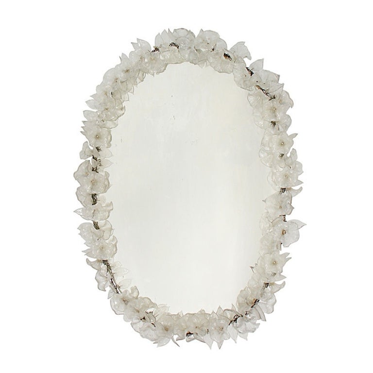 This incredible Murano Mirror features hundreds of handmade clear glass flowers and leaves encircling the original oval mirror. The glass flowers and leaves are attached by a wire framework to a solid wood backing (painted white). The edge of the