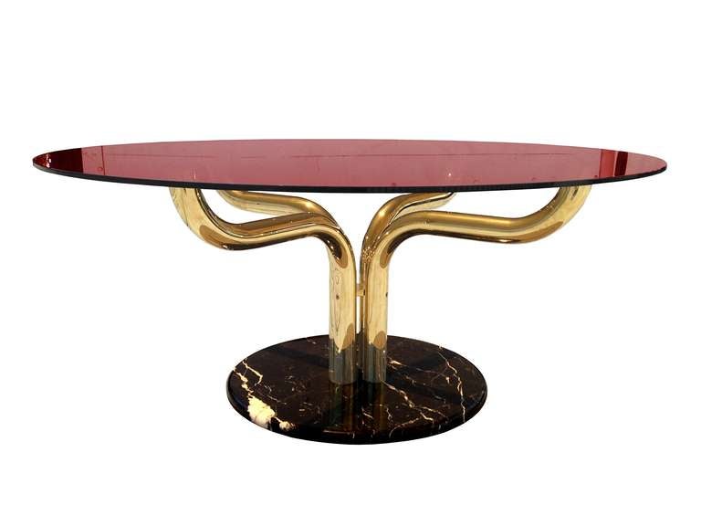 Stunning dining table with a polished marble base with a four arm tubular brass base and a bronzed glass top.

The table has wonderful architectural lines, the thick tubular base has playful lines and the bronzed glass top compliments the rest of
