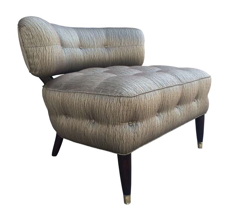The chair has wonderful lines, it is upholstered in a beautiful patterned fabric have the legs stained in a dark espresso color and brass caps.
The chair seats low to the ground, the curvaceous backrest hugs your back inviting you to rest and